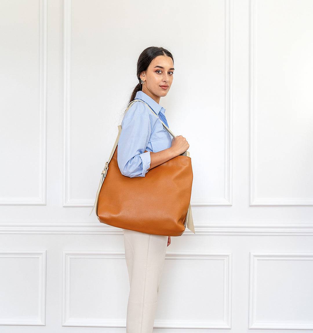 Model carrying the FULERI Convertible AMARA Dual Tote Bag in Sandstone Tan, showcasing its elegant two-tone leather and adjustable straps.